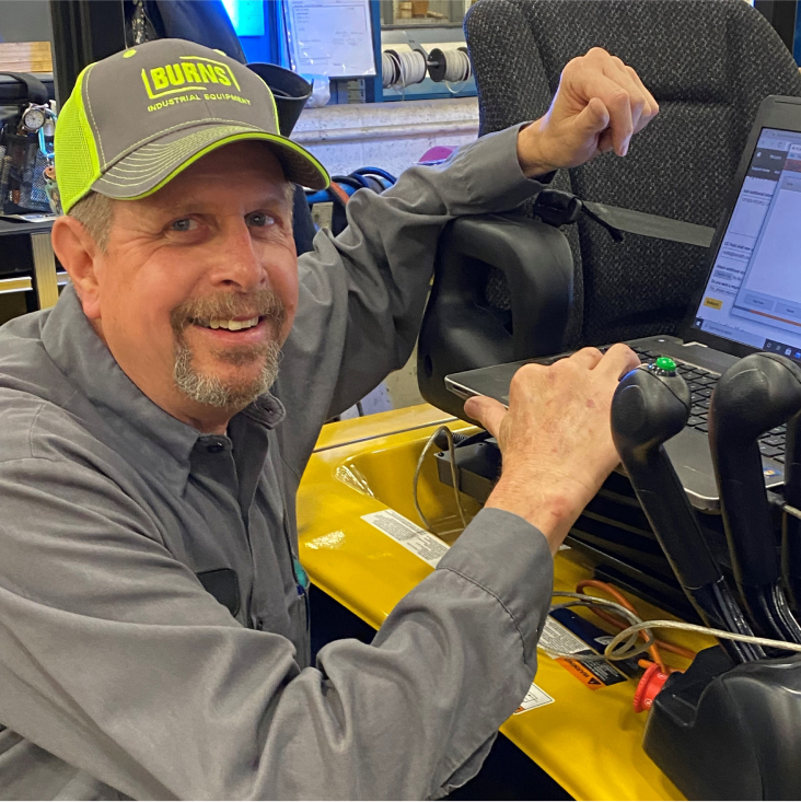 Smiling employee looking at the camera, with laptop open on his truck